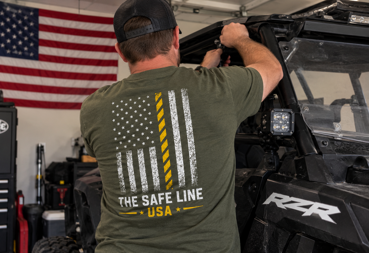 Worker wearing the Army green The Safety Flag Tee while working on an off-road vehicle